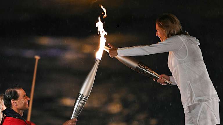 Si vous pensiez que c'était la fin de la relation entre le tennis et l'équipe de France, détrompez-vous. Amélie Mauresmo, double championne du Grand Chelem, directrice du tournoi de Roland Garros et héroïne française, est sortie pour recevoir la flamme des mains de Nadal.