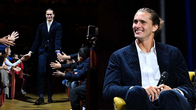 Alexander Zverev porte un costume à fines rayures bleu marine avec un chignon élégant au dos.